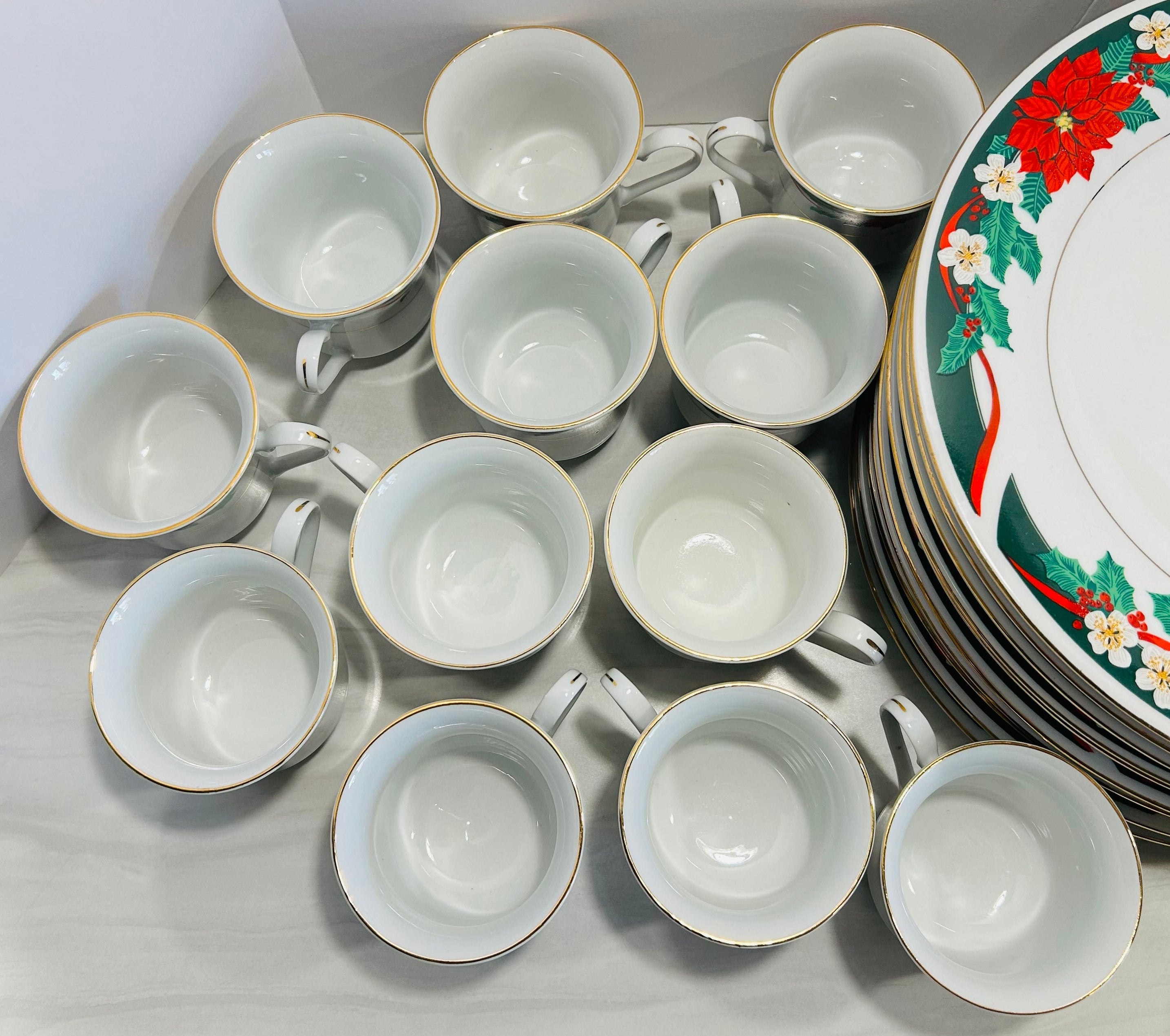 Set of white ceramic cups and a decorative plate with floral patterns on a light background